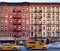 Old apartment buildings in the East Village neighborhood of New York City with taxis driving down the street