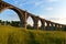 Old arch bridge over a gully overgrown with grass in the evening