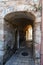 Old arched alley with doorways leading to the sunny street