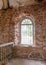 Old arched windows in an abandoned church, iron grilles in front of the windows, crumbling window sills and window sills