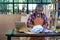 Old Asian craftsman stand in front of laptop and thinking about his process for working with paper and some tools in the workplace