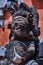 An old Asian statue of Buddha stands in the garden of a temple adorned with flowers