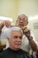 Old barber cutting hair to client in barber shop