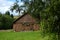 Old barn brown wall wood background surrounded by green trees. The barn is decorated with flowers and greenery. Bright
