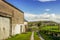 An old barn in Cumbria on a sunny day with a wooden gate and distant hills.