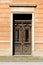 Old baroque style wooden front entrance doors with clear glass and metal decorative protective bars mounted on dilapidated family