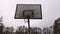 Old basketball hoop on grunge destroyed schoolyard. Gray rainy sky sad town mood. Metal chain basket on hoop. Outdoors