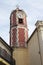 Old beautiful clock tower in Italy. Near the entrance to the Catholic Church. Tall tower in summer in a small town in southern