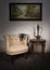 Old beige armchair, brass teapot, framed painting and antique table