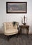 Old beige armchair, brass teapot, framed painting and antique table