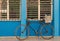 Old bicycle leaning against barred,shuttered windows and blue wall