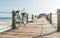 Old bicycle on wooden sea pier and a happy smiling man dressed in light summer clothes sitting and enjoying time on background.