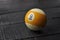 Old billiard ball number 9 striped white and yellow on black wooden table background, copy space