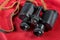 Old binoculars with strap placed on red cloth