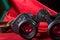Old binoculars with strap placed on red cloth. Close up. Selective focus on the sign mark