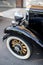 An old black luxury retro car with wooden wheel spokes stands at a street exhibition of vintage cars