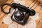 Old black phone on lace tablecloths and wooden background