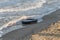 Old black rubber tire left on beach, environment pollution concept, selective focus, color toned picture. Discarded old tyre in bl