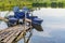 Old blue catamaran stands on surface of lake near wooden bridge. Summer landscape.