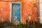 Old blue colored door in abandoned orange house