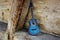 An old blue jazz guitar leaning against the wood of the barn