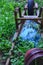 Old blue metal wheelbarrow upside down with weeds growing around it.