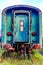 Old blue passenger carriage with front door on disused train tracks at old station