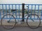 Old blue retro bike with rust places chained lock to the bars on the waterfront