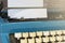 An old blue typewriter and trash paper on wooden desk. Copy space