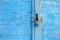 Old blue wooden plank gate with a padlock