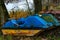 Old boats and catamarans are rusting in the open. Dump in the forest at the foot of the river bank of outdated water equipment.