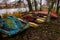 Old boats and catamarans are rusting in the open. Dump in the forest at the foot of the river bank of outdated water equipment.