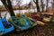 Old boats and catamarans are rusting in the open. Dump in the forest at the foot of the river bank of outdated water equipment.