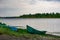 Old boats made of wood and metal on the river Bank among rocks and vegetation. Parked water transport in nature.