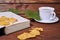 Old book and autumn leaves lie on a wooden table. Nearby is a mug of tea and saucer. concept