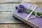 Old book decorated with lavender flowers and tied with jute twine on wooden table.