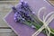 Old book decorated with lavender flowers and tied with jute twine on wooden table.