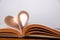 Old book and heart-shaped pages. White background. Wooden Table. Closeup. Copy space