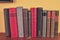 Old books on wooden shelf. Antique books on yellow and claret background