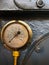 Old brass pressure meter with a round scale with numbers on an aged dial on a grey steel background