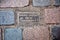 Old brass Smoke Outlet sign embedded into an old brick floor at Camden Market