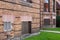 Old brick apartment building with basement windows filled with mixed bricks, vents, and wood boards