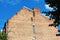 Old brick building walls with windows, green trees, blue cloudy sky