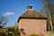 Old brick built dove cote with terracotta tiled roof against blue sky - image
