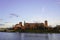 Old brick castle on the river Bank, against the blue sky at sunset. building of the old Polish town, high castle walls, clock