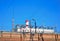 Old brick fence on a background of blue sky and electrical power station. Industrial tourism.