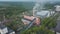 Old brick industrial buildings with tall chimney stack surrounded by forest. Aerial view from above.