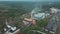 Old brick industrial buildings with tall chimney stack surrounded by forest. Aerial view from above.