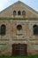 An old brick non-residential building. An ancient historical building. Unusual arched windows and large wooden gates in an ancient