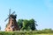 Old brick windmill on field on blue sky background